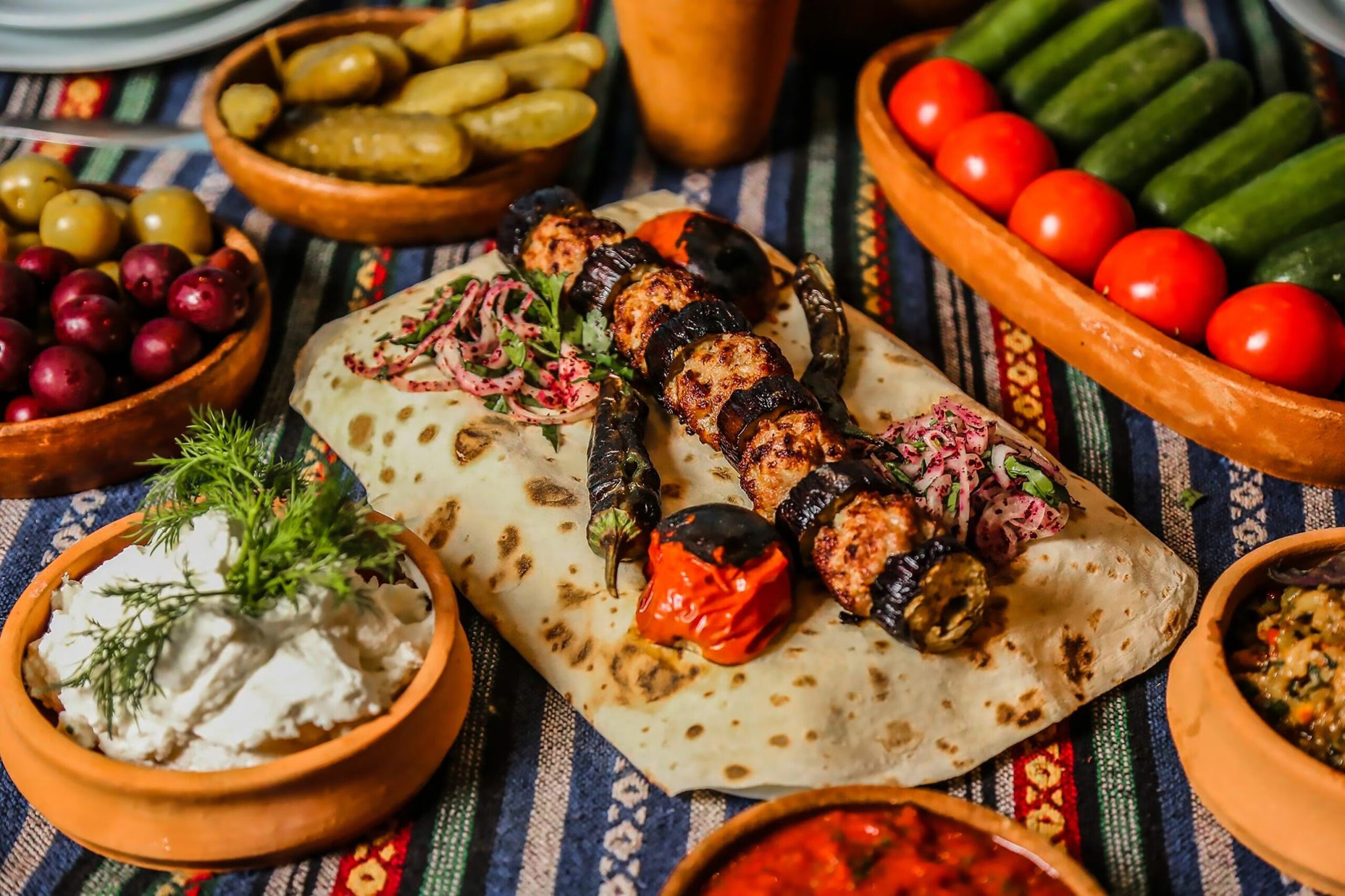 A variety of traditional Azerbaijani dishes served on a colorful table, including plov, dolma, and kebabs.